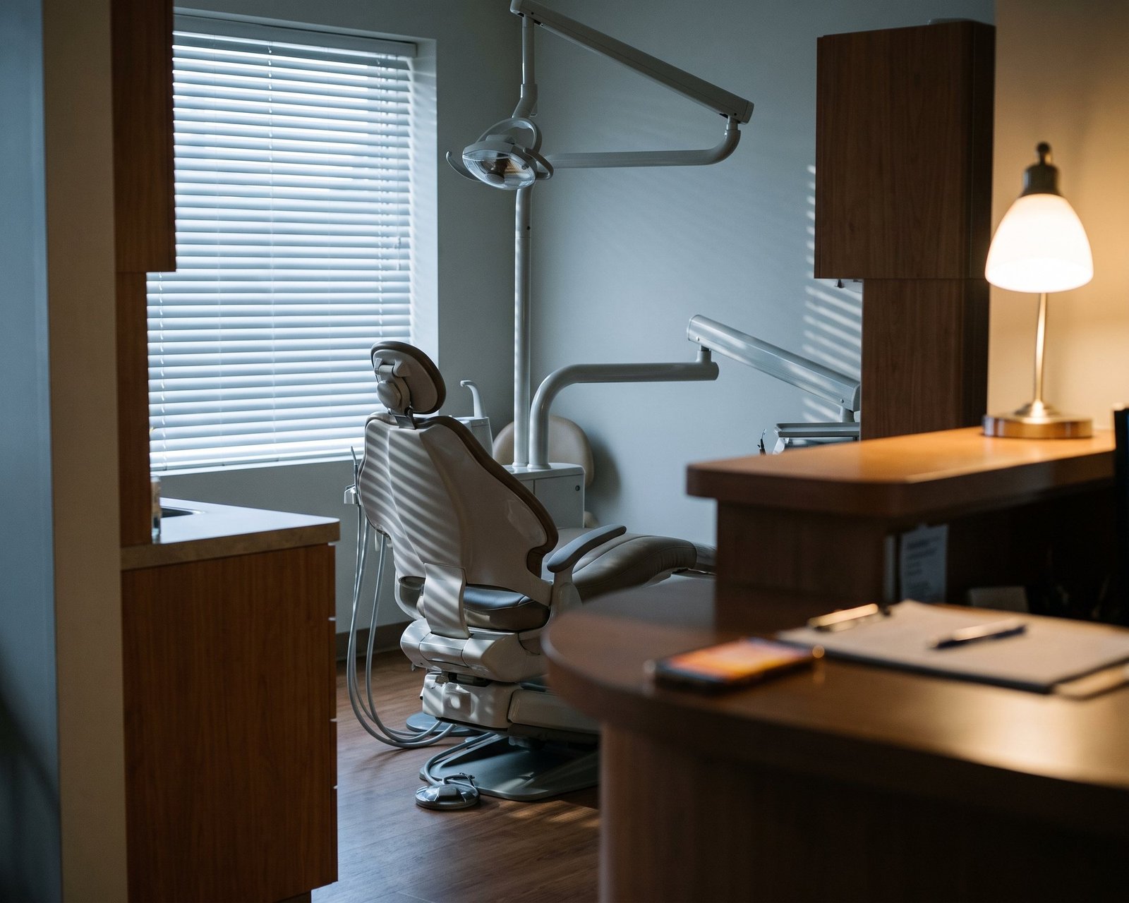 Sala de atendimento odontológica ao amanhecer, a cadeira vazia e o celular aceso no balcão
